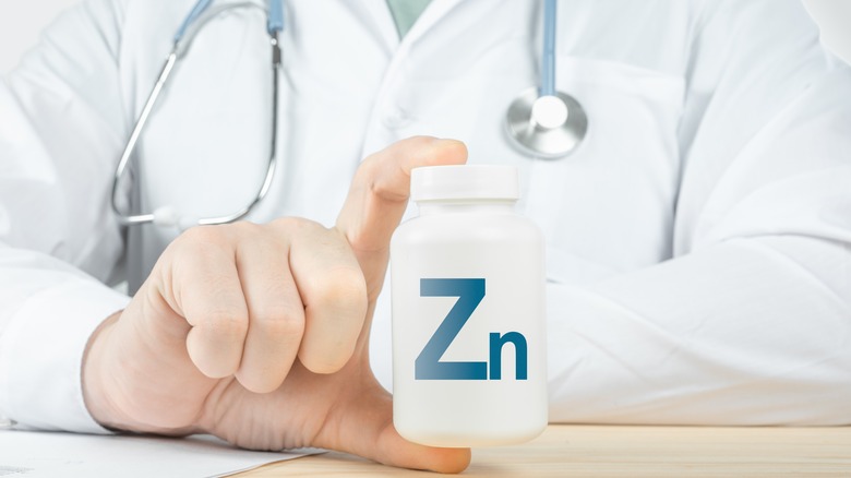 doctor holding supplement bottle with Zn