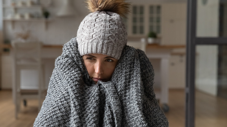 cold woman with hat wrapped up in blanket