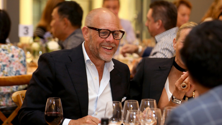 Alton Brown smiling at dinner table