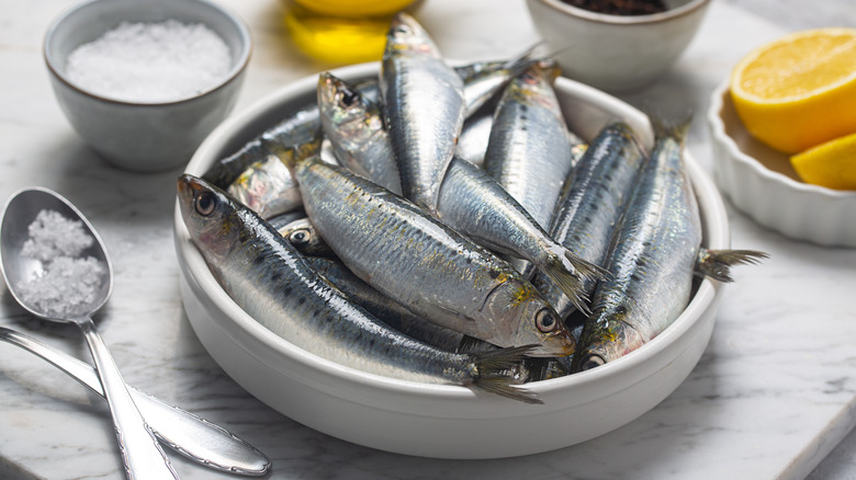 Sardines in dish with salt and lemons in bowls