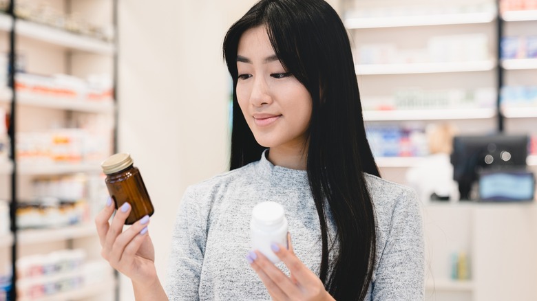 asian woman choosing between two medications