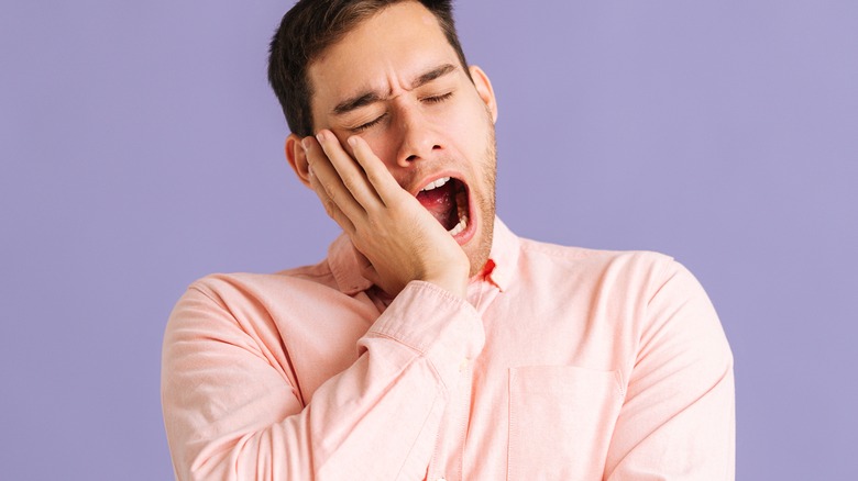 man yawning against purple background