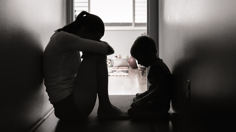 silhouette of grieving mother and son sitting on floor