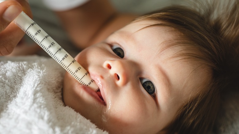 baby getting oral medicine with syringe