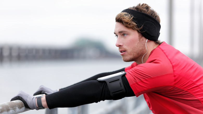 man stretching while dressed in cold weather layers