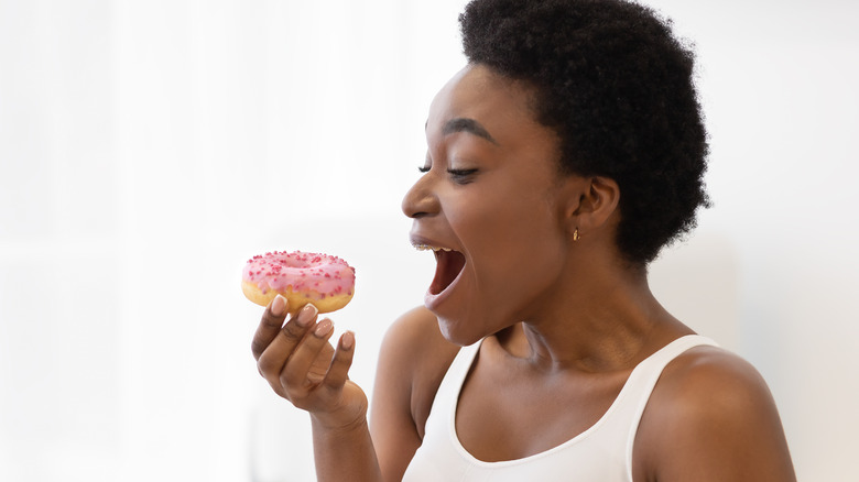 woman excited to bite into a donut