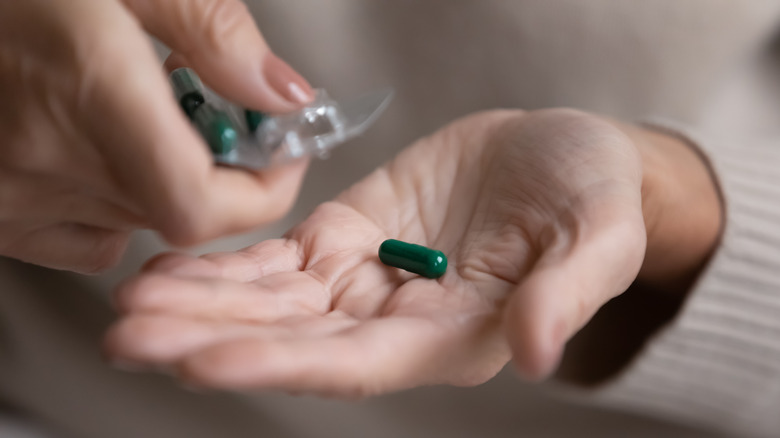 Hand holding green pill