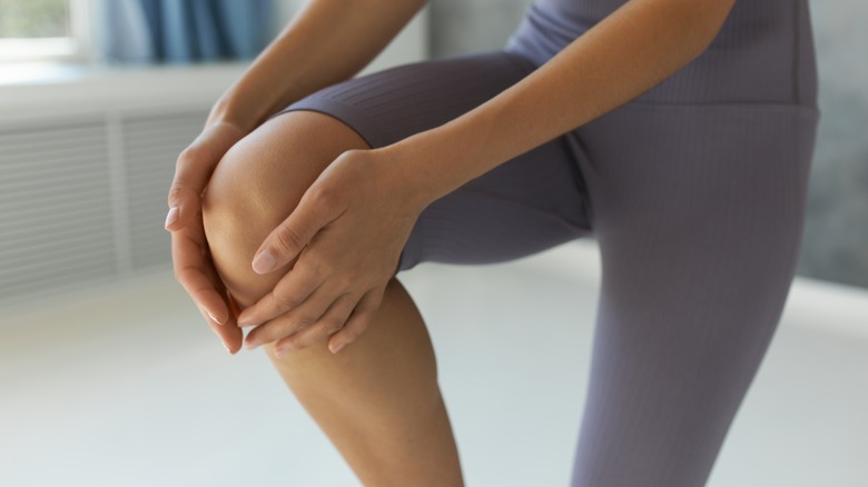 woman in fitness clothing holding her knee