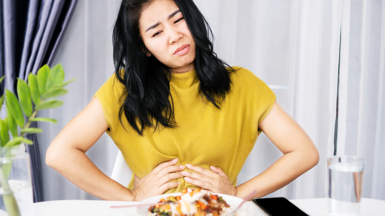 woman holding her stomach feeling acid reflux