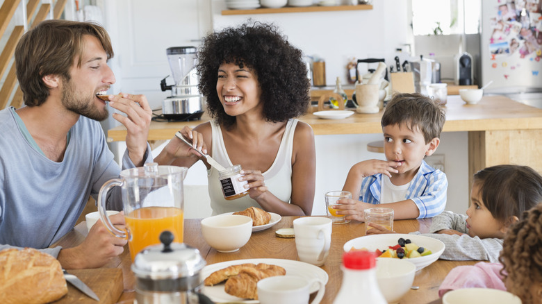 A family enjoying breakfast with juice, bread, and fruit