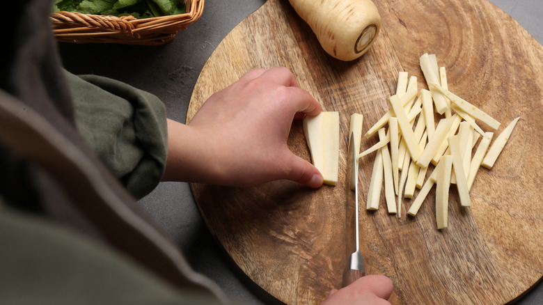 A woman cutting parsnips on a wooden board