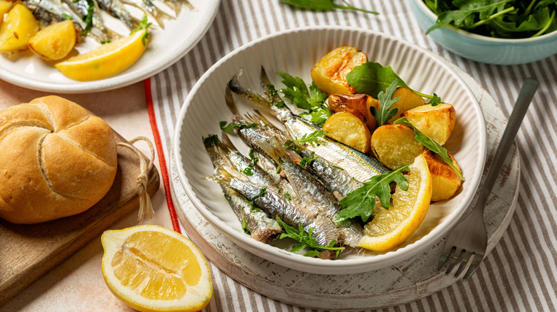 Sardines in a small bowl with lemon and potatoes