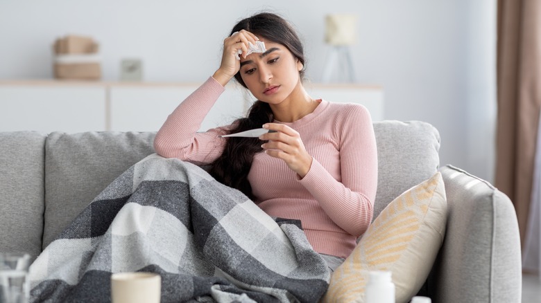 Young woman on couch with a thermometer