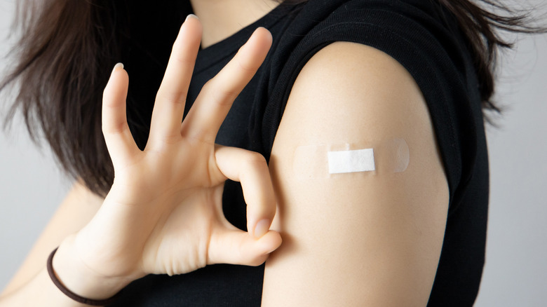 Woman giving okay sign by her vaccination location