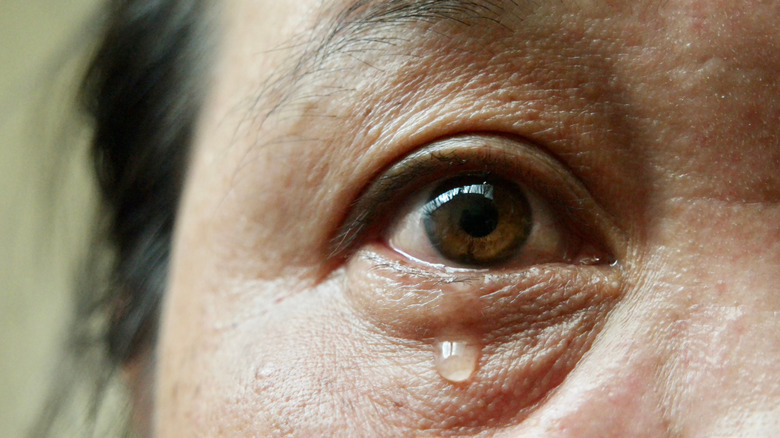 Wide-eyed woman with teardrop falling down her cheek