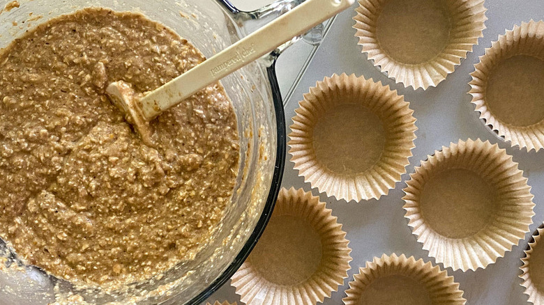 Muffin batter in a bowl next to a lined baking sheet