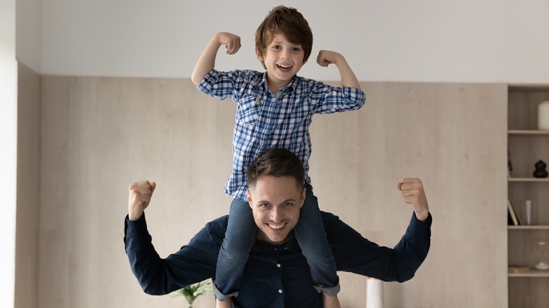 Smiling child sitting on man's shoulders