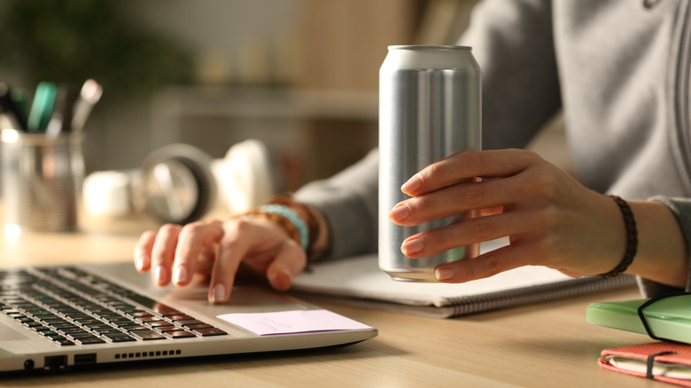 A woman holds a silver soda can