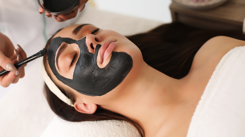 Woman getting charcoal mask facial