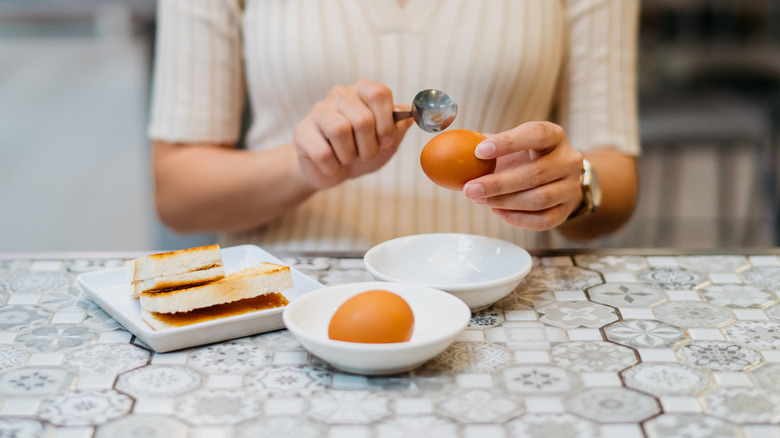 woman cracking a hard-boiled egg