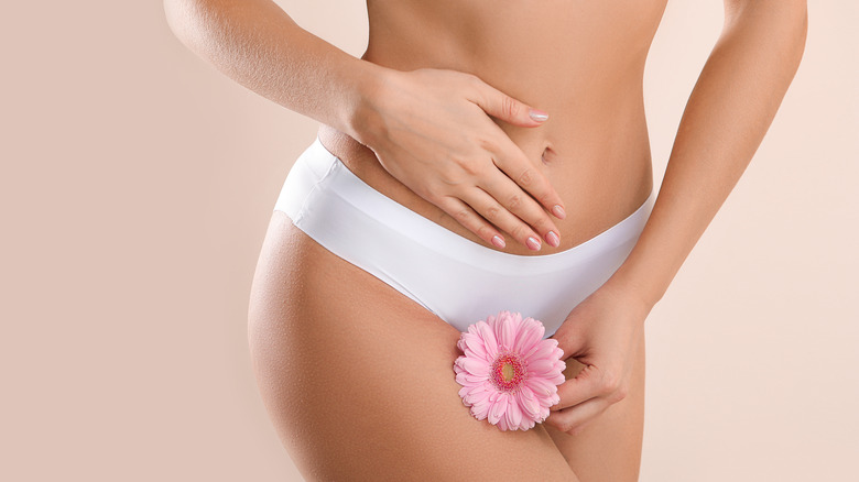 Woman holding a flower beneath her belly