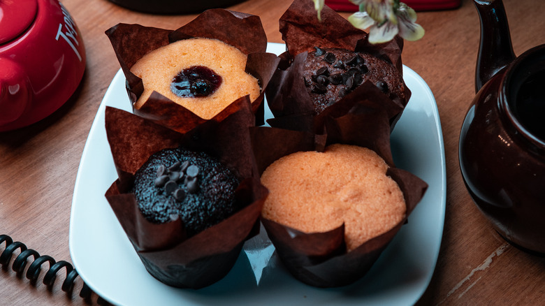 Four packaged muffins sit on a desk