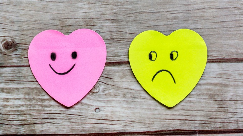 happy and sad hearts on wooden background