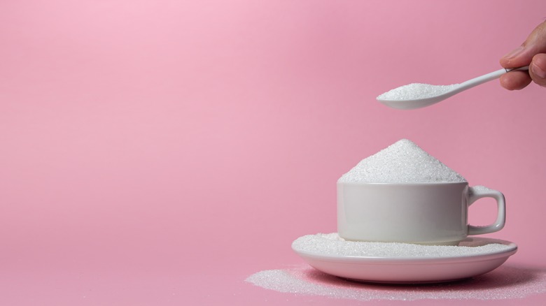 white cup with sugar on pink background