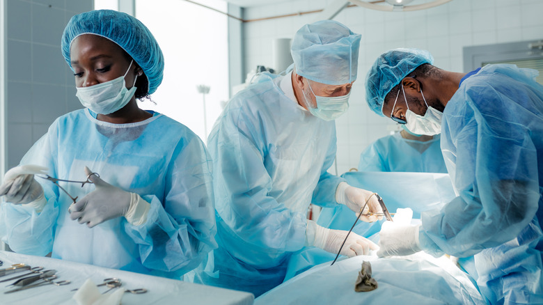 Three surgeons conducting organ transplant surgery