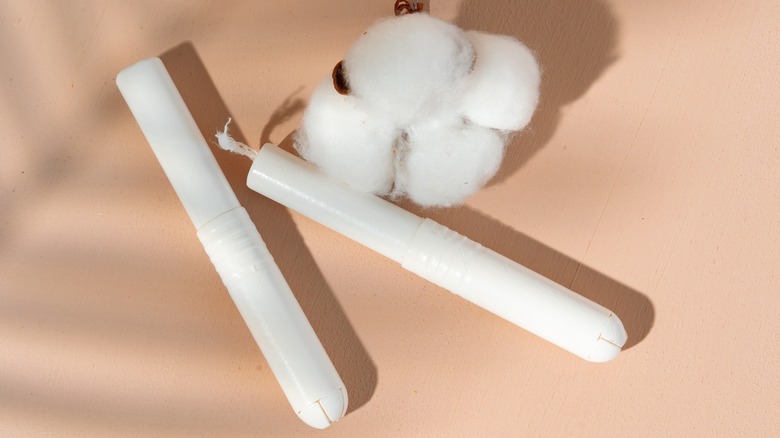 Two tampons beside a cotton flower