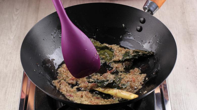 woman sautéing food with plastic spoon