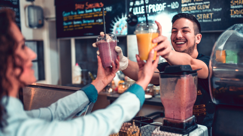man giving smoothies to customers in smoothie bar