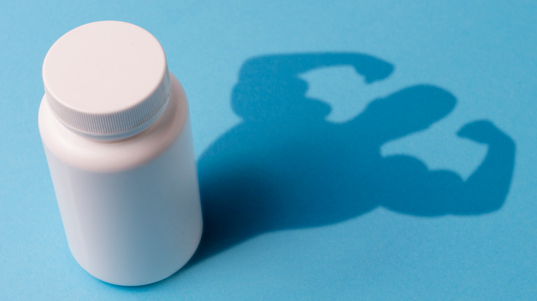 bottle of pills with a muscular male shadow 