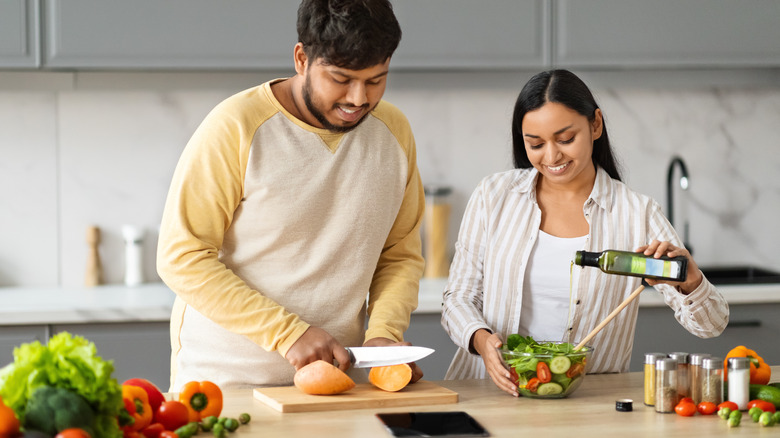 couple making meal with man cutting sweet potato