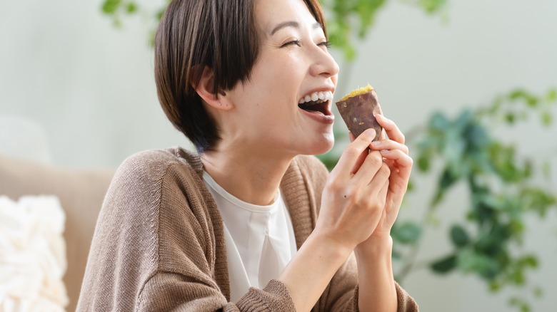 A young woman eating a sweet potato