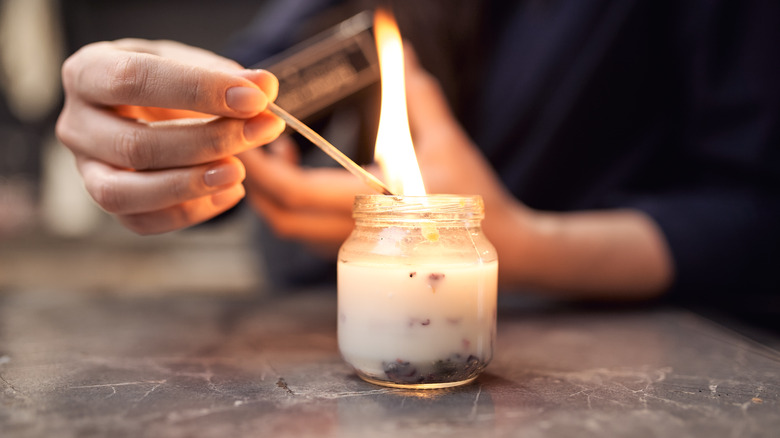 woman's hand lighting a candle