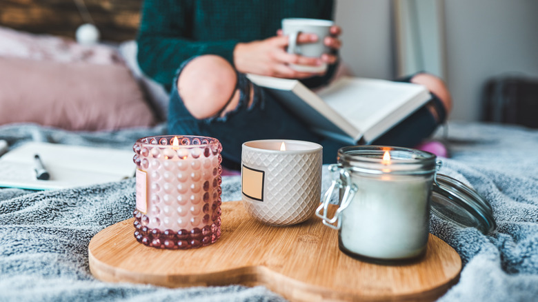 three lit candle jars with woman in background