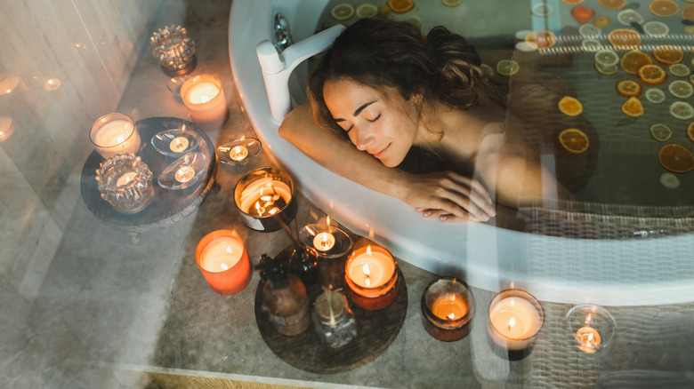 woman in a bathtub surrounded by candles