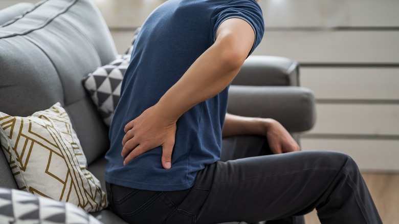 Person on couch holding their back