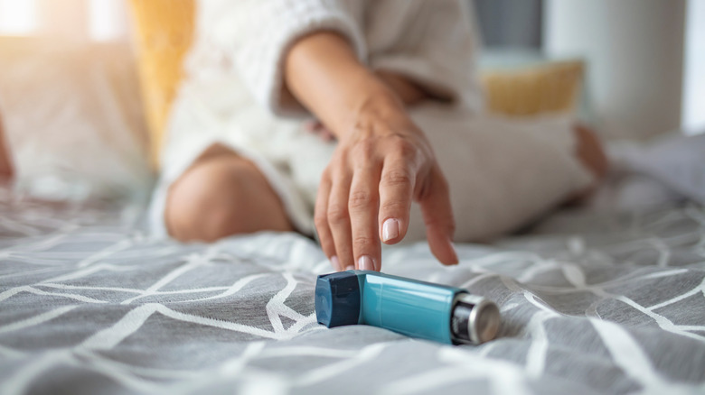 Person reaching for asthma inhaler in bed