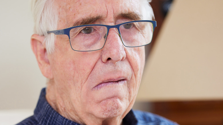 elderly man in glasses with left side facial drooping