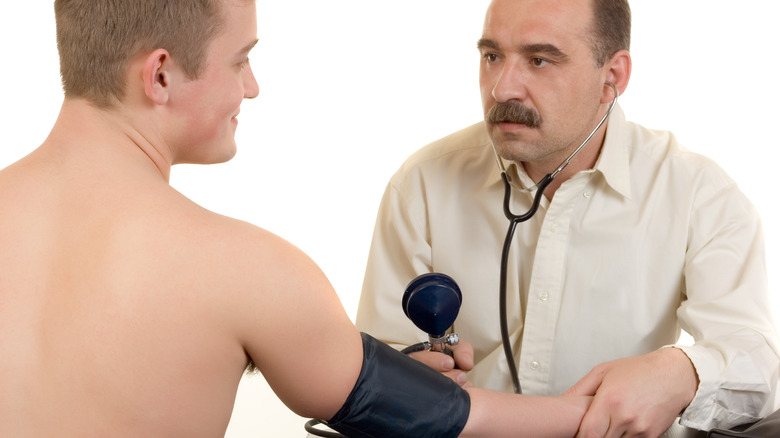 doctor taking blood pressure on a young male