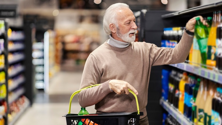 Elderly man grocery shopping in beverage aisle 