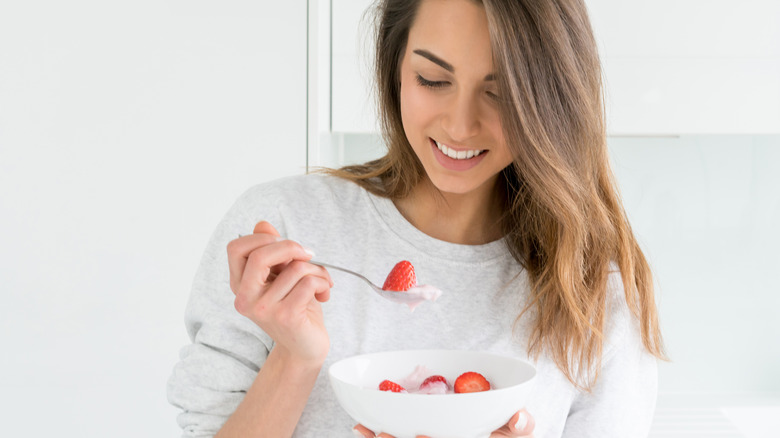 woman eating plain yogurt with fruit