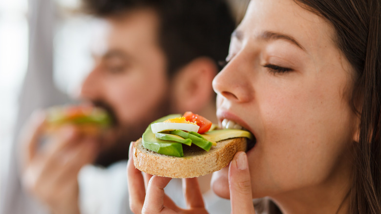 young woman and young man eating avocado toast