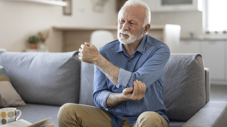 Elderly man rubbing elbow in pain