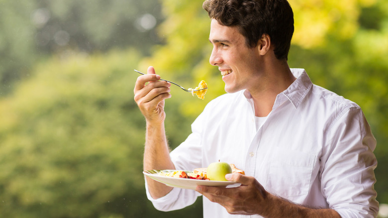 man eating scrambled eggs with an apple on his plate