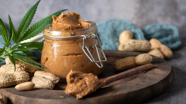 jar of fresh ground peanut butter on a wood plate