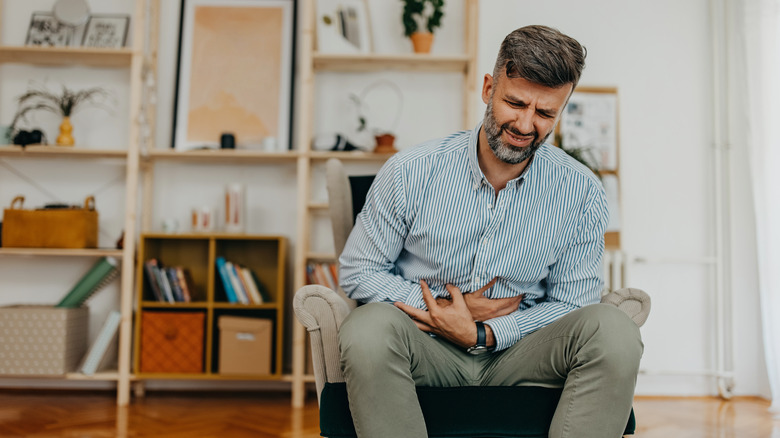 man holding abdomen and looking pained