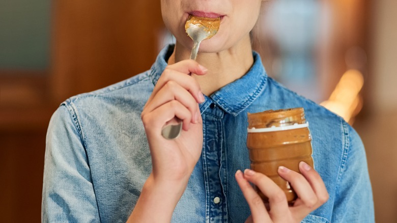 Woman eating spoonful of peanut butter